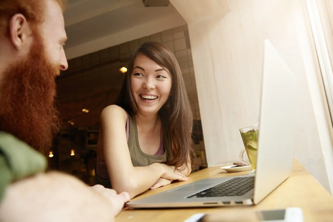 In einem Café sitzen eine brünette Frau und ein rothaariger Mann.