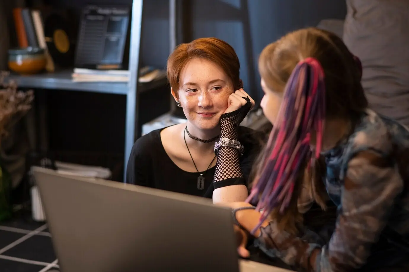 Seitenansicht von Freunden mit einem Laptop drinnen.